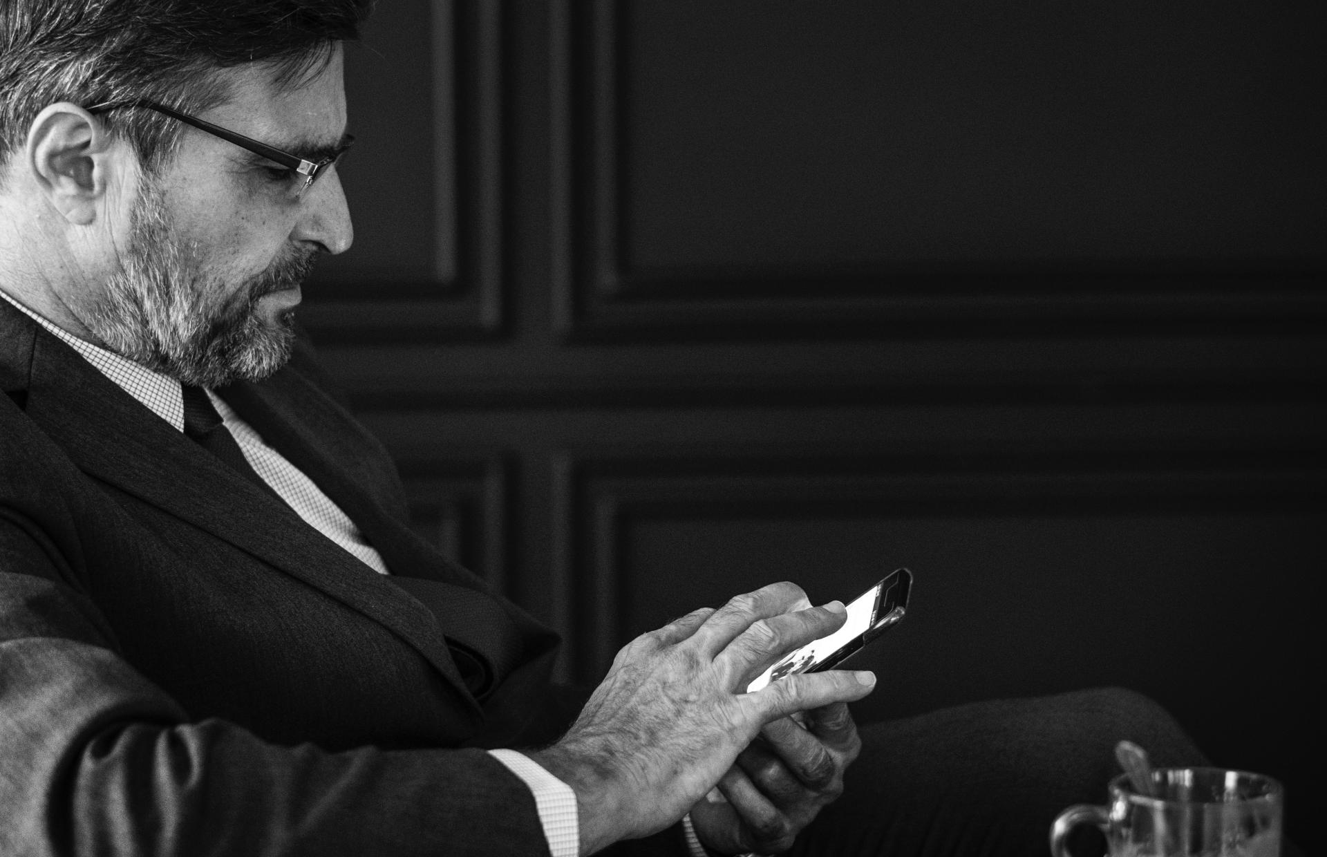 A business person sits with their phone in one hand.