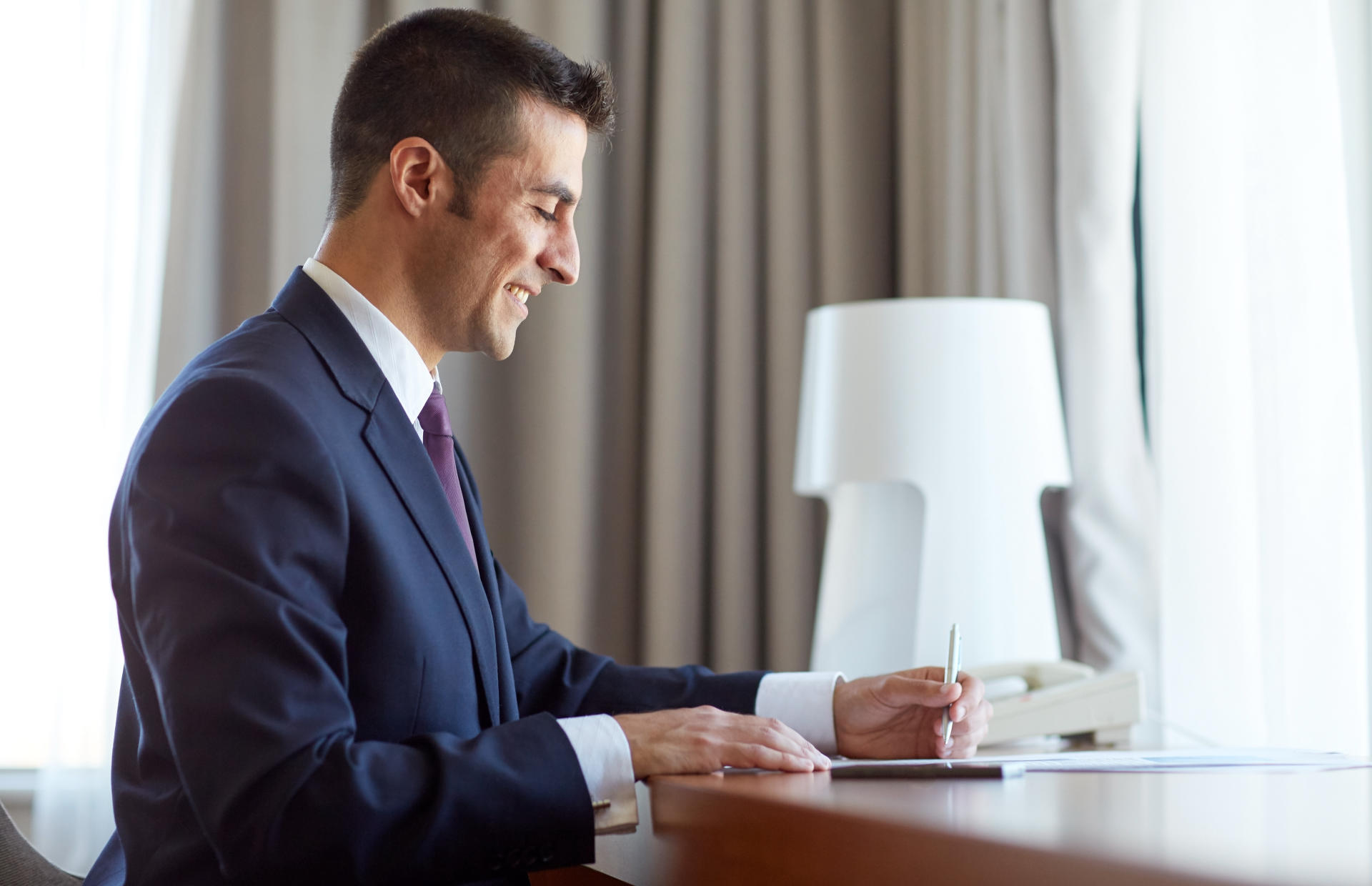 A business person sits at a hotel room table.