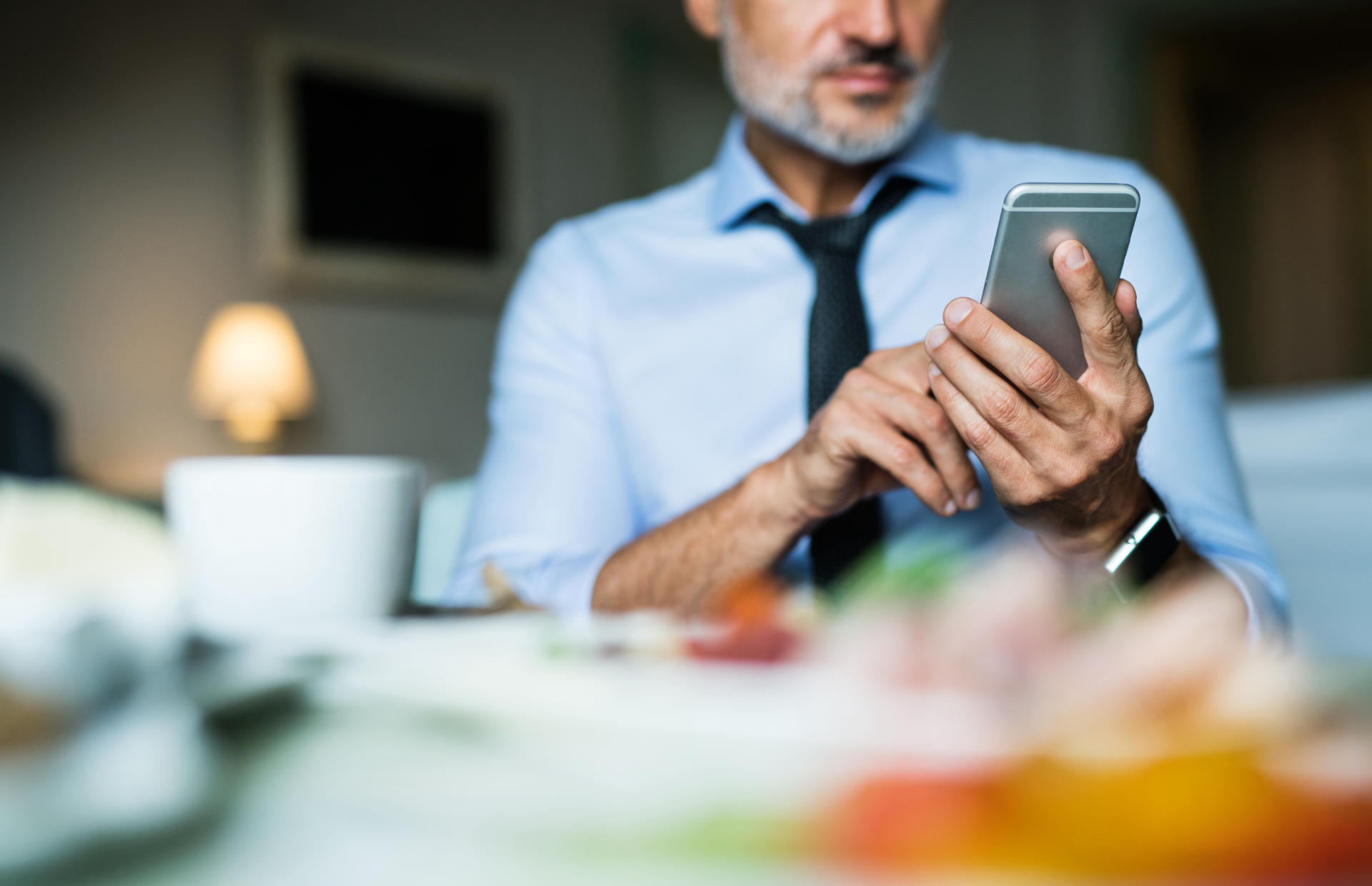 A hotel guest holds their phone while sitting down at a table.
