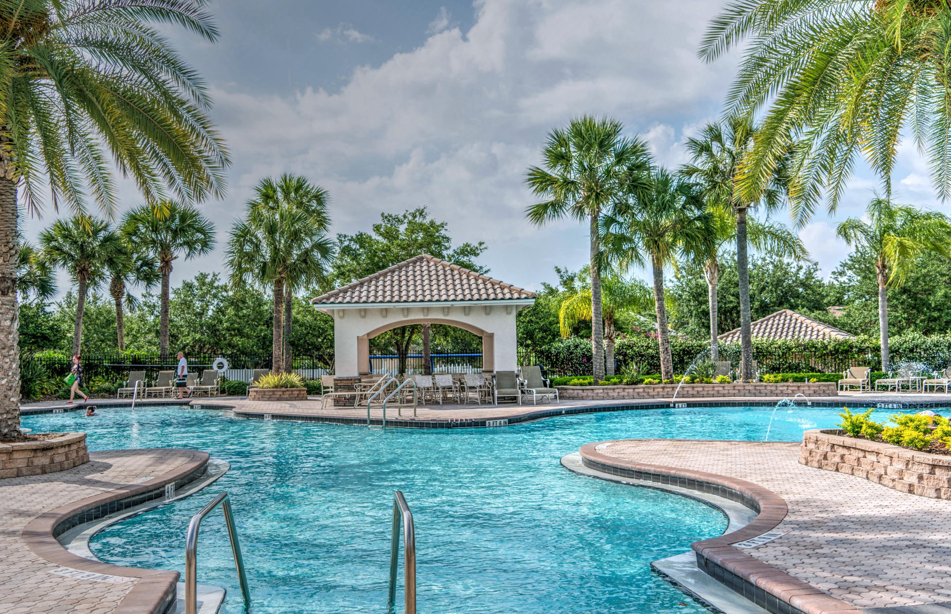 A hotel pool is surrounded by palm trees.