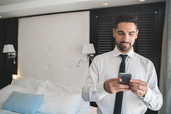 Businessman uses cell phone in hotel room