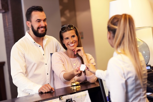 Couple at reception desk in hotel.